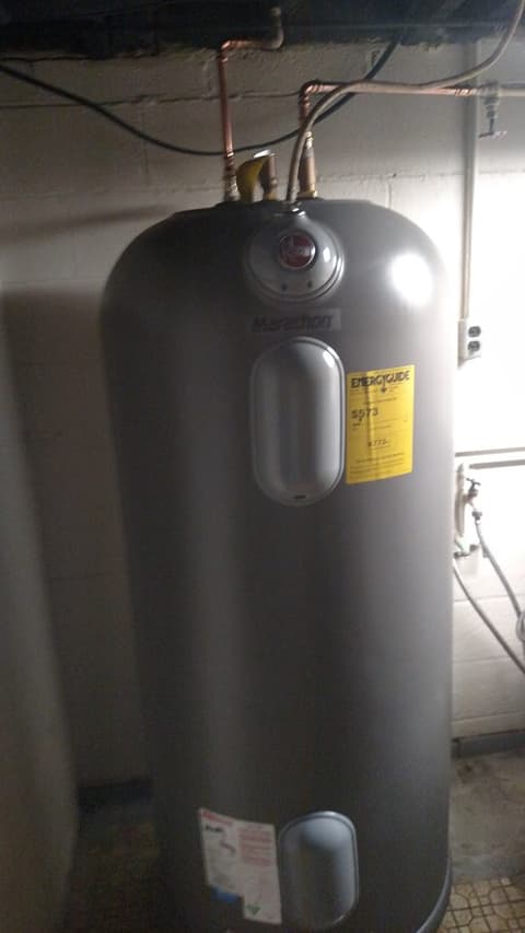 Tall electric water heater installed in basement